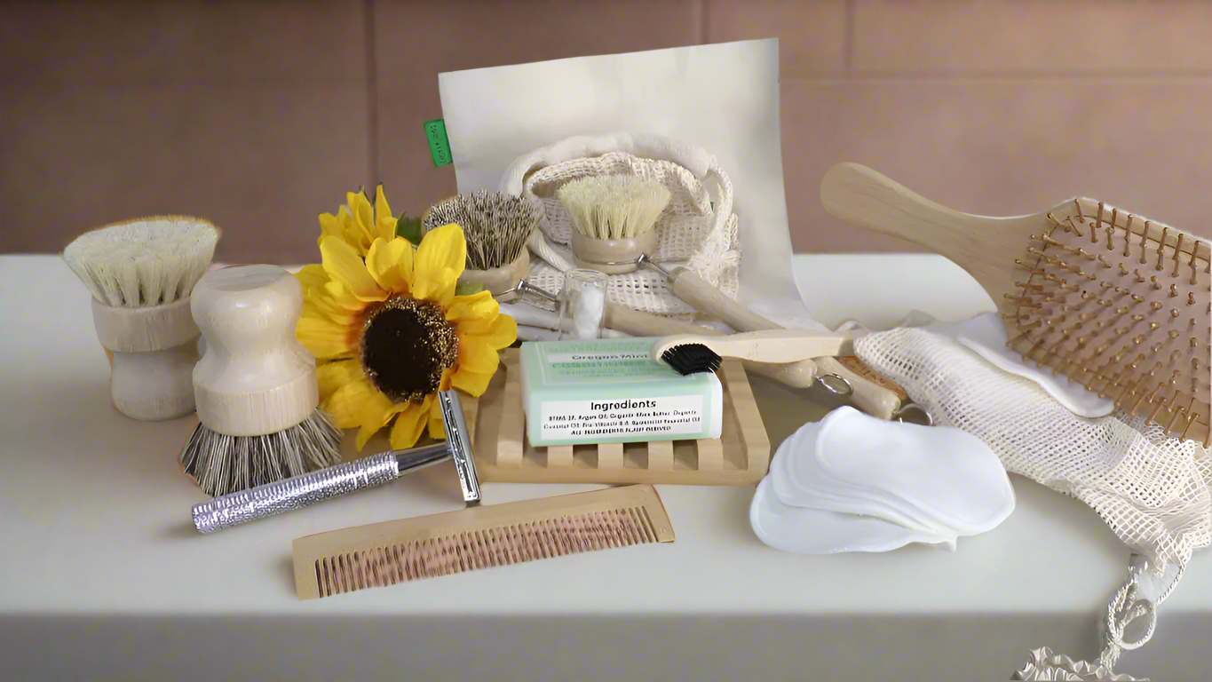 Zero-waste bathroom essentials featuring eco-friendly grooming tools including wooden hairbrush, bamboo comb, natural dish brushes, reusable cotton pads, safety razor, wooden soap dish with organic mint soap, mesh washcloth, and decorative sunflower. Sustainable plastic-free personal care alternatives displayed on white surface with product information card showing natural ingredients.